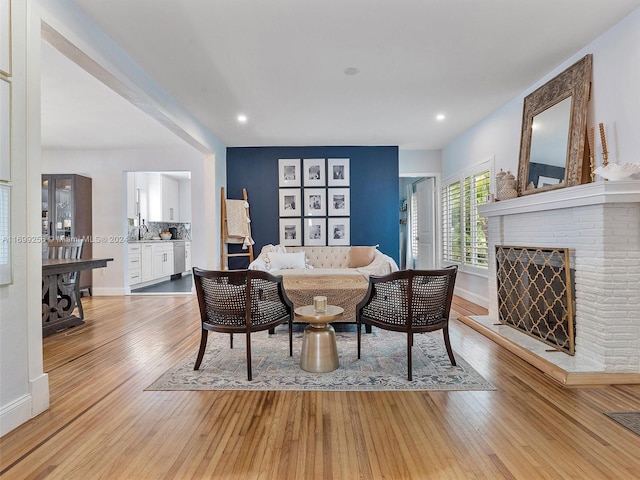 living room with a brick fireplace, light hardwood / wood-style flooring, and sink