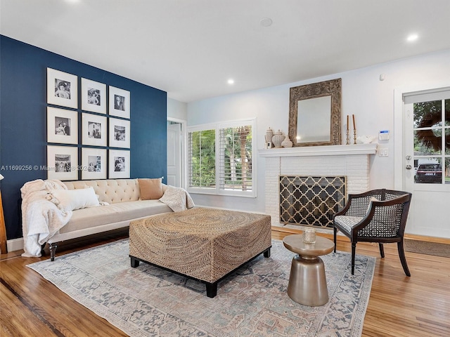 living room featuring wood-type flooring and a brick fireplace