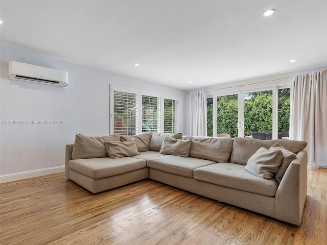 living room with plenty of natural light, light hardwood / wood-style floors, and a wall mounted air conditioner