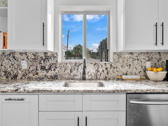 kitchen featuring stainless steel dishwasher, light stone countertops, white cabinetry, and sink