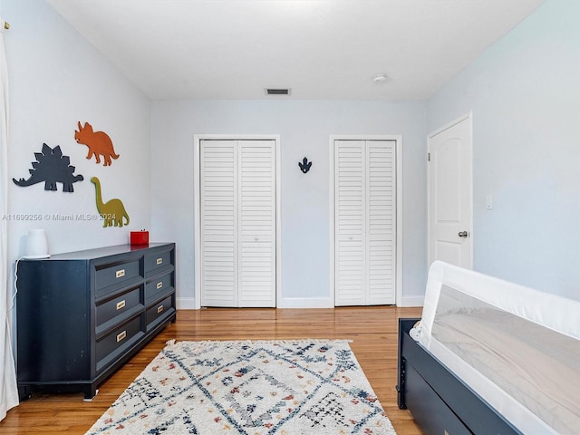 bedroom featuring two closets and light hardwood / wood-style flooring