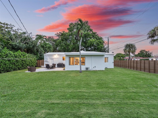 back house at dusk with a yard and a patio