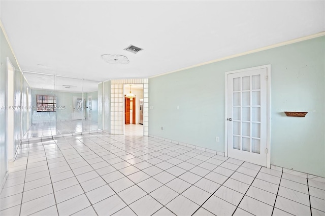 empty room with light tile patterned floors, visible vents, and ornamental molding