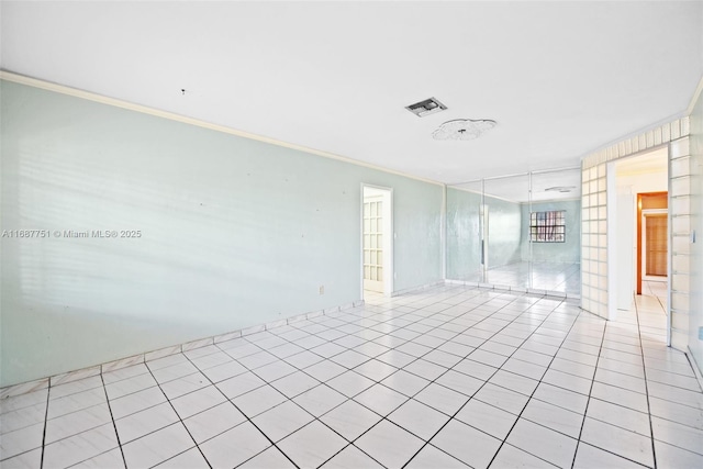 empty room featuring crown molding, light tile patterned floors, and visible vents