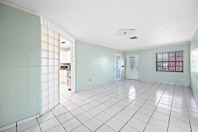 empty room with light tile patterned flooring, visible vents, and ornamental molding