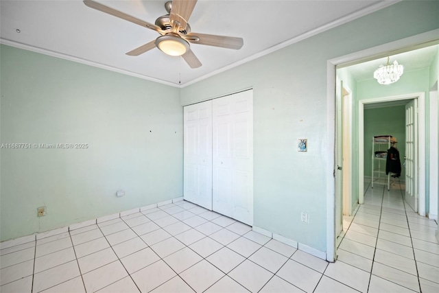 unfurnished bedroom with light tile patterned flooring, ornamental molding, ceiling fan with notable chandelier, and a closet