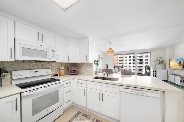 kitchen with kitchen peninsula, white appliances, sink, light tile patterned floors, and white cabinets