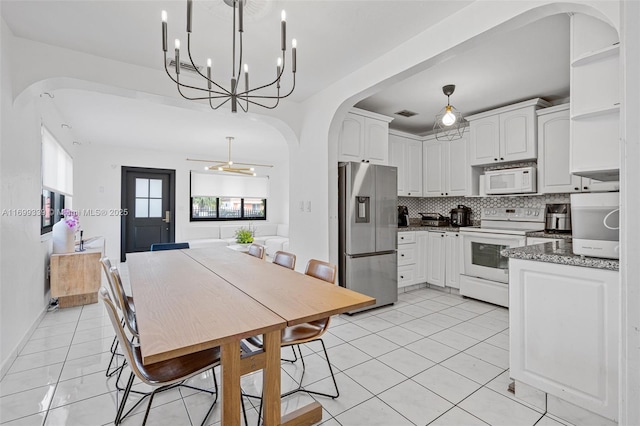 kitchen with white appliances, stone countertops, white cabinets, hanging light fixtures, and decorative backsplash