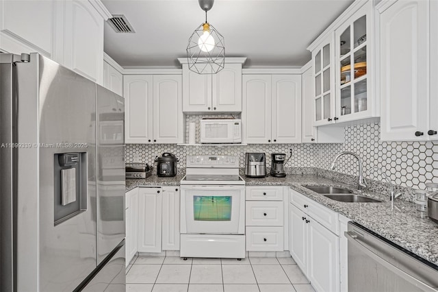 kitchen featuring hanging light fixtures, stainless steel appliances, light stone countertops, white cabinets, and sink