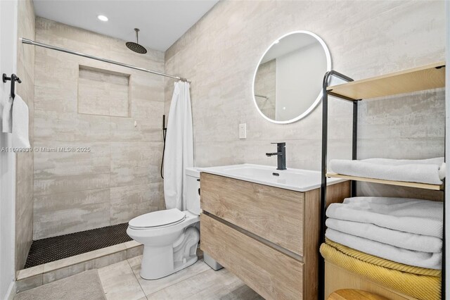 bathroom with a shower with shower curtain, tile patterned floors, vanity, tile walls, and toilet