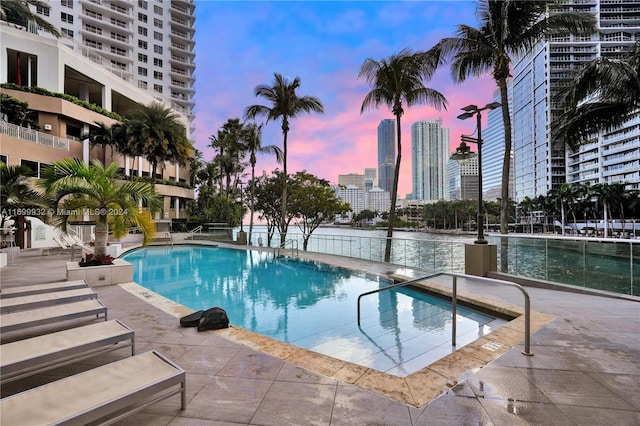 pool at dusk with a patio area