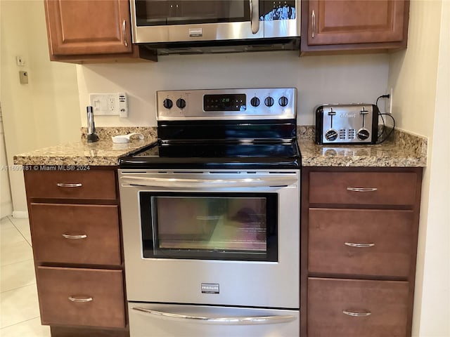 kitchen featuring light tile patterned floors, stainless steel appliances, and light stone counters