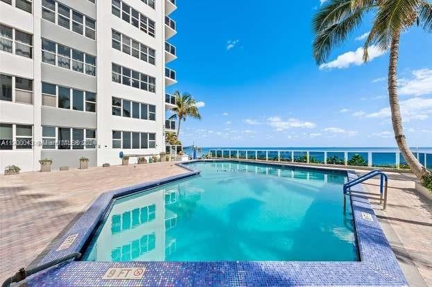 view of pool featuring a water view and a patio