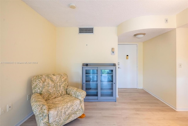 living area with a textured ceiling and light wood-type flooring