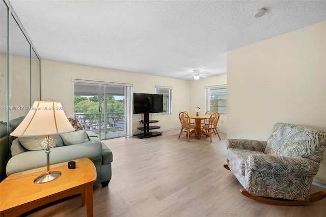 living room with plenty of natural light, a textured ceiling, and light wood-type flooring