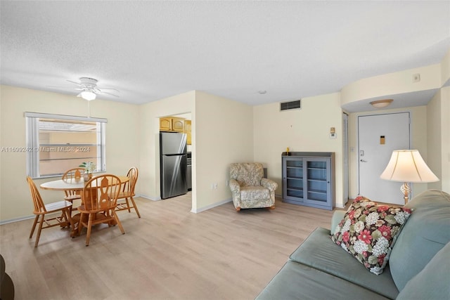 living room with ceiling fan, light hardwood / wood-style floors, and a textured ceiling