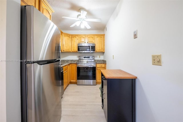 kitchen with butcher block counters, stainless steel appliances, ceiling fan, and light hardwood / wood-style floors