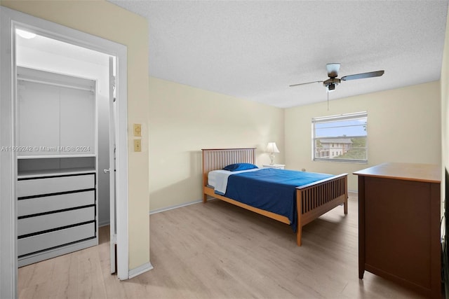 bedroom with ceiling fan, light hardwood / wood-style floors, and a textured ceiling