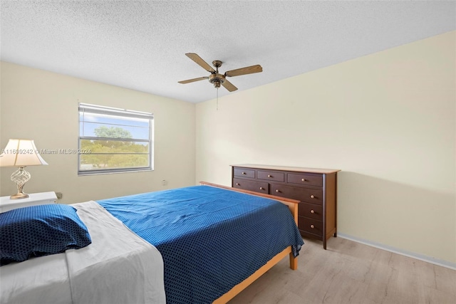 bedroom featuring ceiling fan, light hardwood / wood-style floors, and a textured ceiling