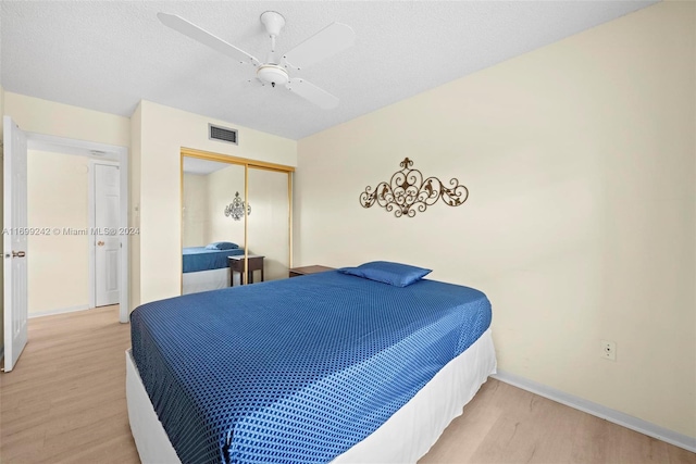 bedroom with hardwood / wood-style floors, a textured ceiling, a closet, and ceiling fan