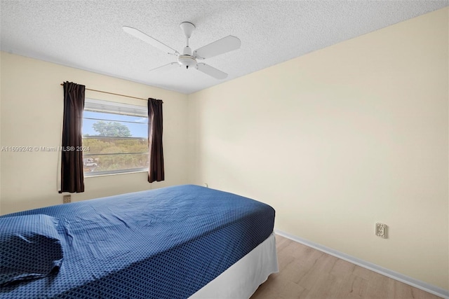 bedroom featuring a textured ceiling, light wood-type flooring, and ceiling fan