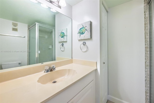 bathroom featuring vanity, toilet, and a shower with door