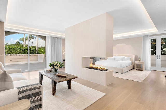 bedroom with french doors, wood-type flooring, access to exterior, and a tray ceiling