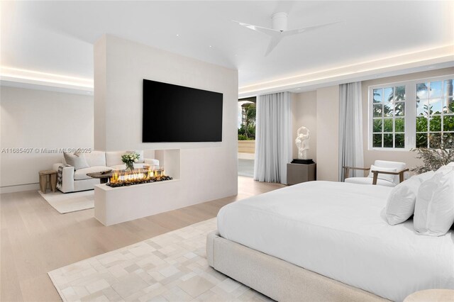 bedroom featuring light hardwood / wood-style flooring, a raised ceiling, and ceiling fan