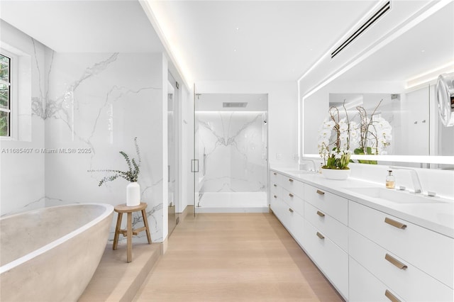 bathroom featuring hardwood / wood-style flooring, vanity, and plus walk in shower