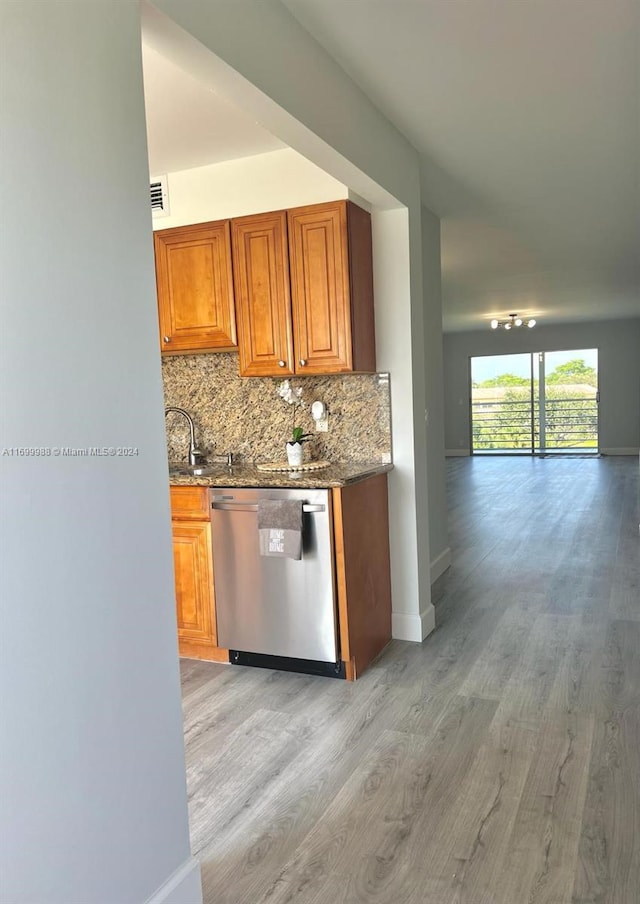 kitchen with light wood-type flooring, tasteful backsplash, stainless steel dishwasher, and sink