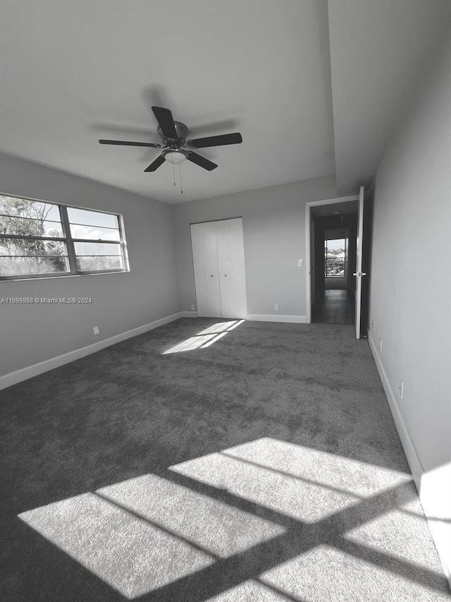 spare room with dark colored carpet and ceiling fan