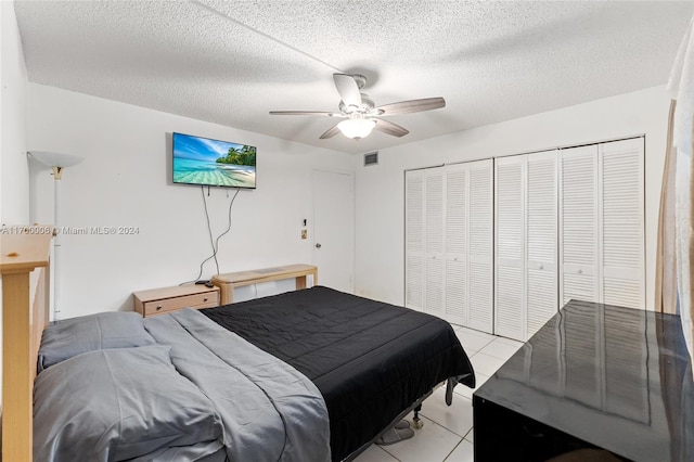 tiled bedroom featuring ceiling fan, a closet, and a textured ceiling