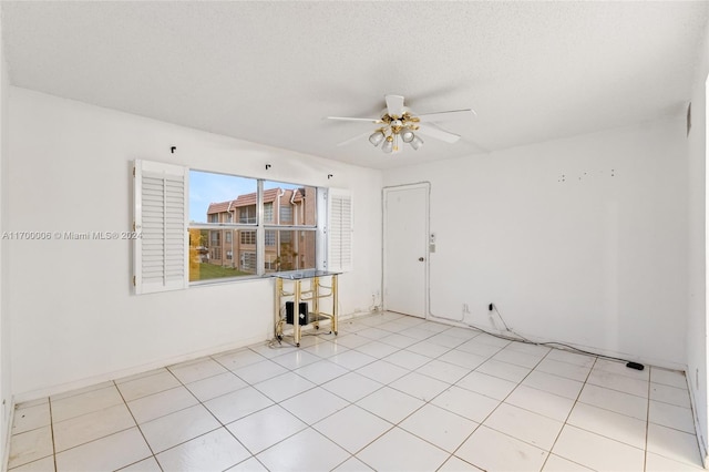 tiled spare room with a textured ceiling and ceiling fan