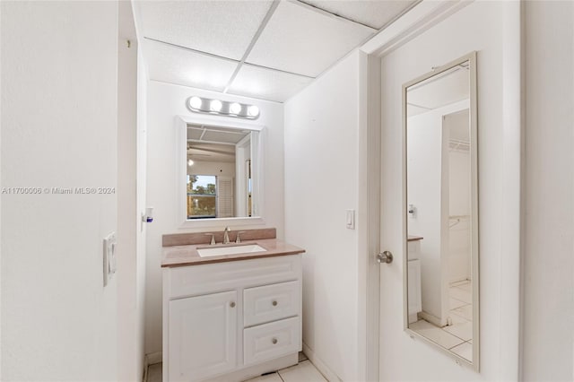 bathroom featuring tile patterned flooring, vanity, and a paneled ceiling