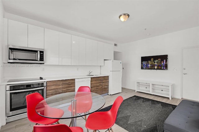 kitchen featuring white cabinets, sink, stainless steel appliances, and light hardwood / wood-style flooring