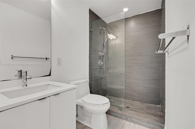 bathroom with a tile shower, vanity, and toilet