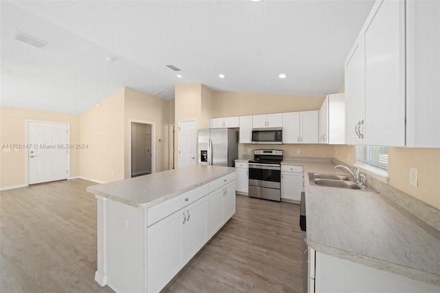 kitchen with sink, a kitchen island, lofted ceiling, white cabinets, and appliances with stainless steel finishes