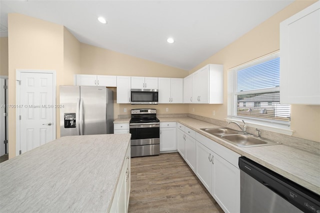 kitchen with white cabinetry, sink, light hardwood / wood-style flooring, vaulted ceiling, and appliances with stainless steel finishes