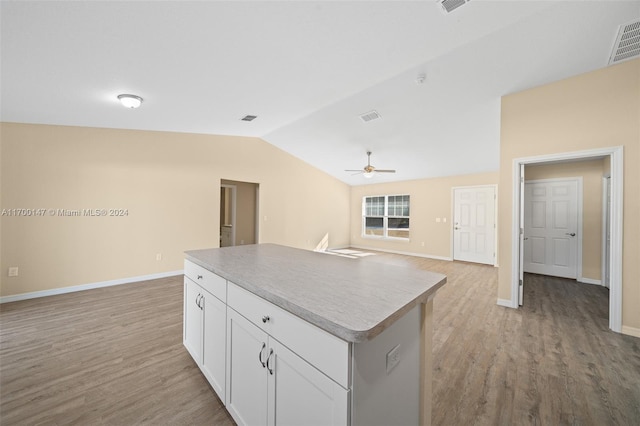 kitchen featuring ceiling fan, a center island, vaulted ceiling, white cabinets, and light wood-type flooring