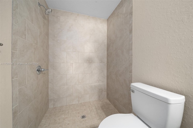 bathroom with a tile shower and toilet