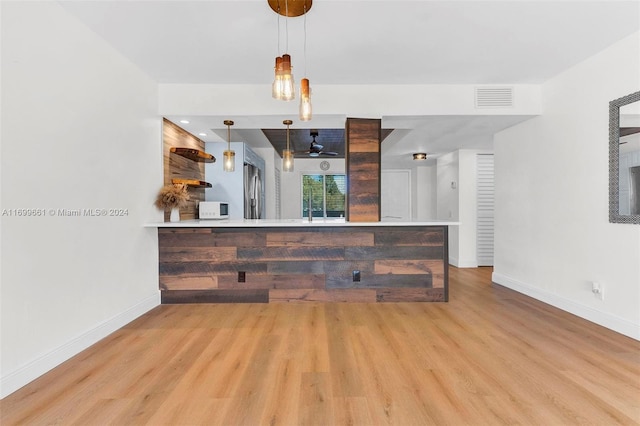 bar featuring light hardwood / wood-style flooring and hanging light fixtures