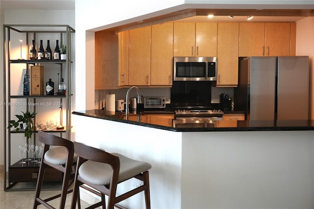 kitchen with sink, dark stone countertops, kitchen peninsula, and stainless steel appliances