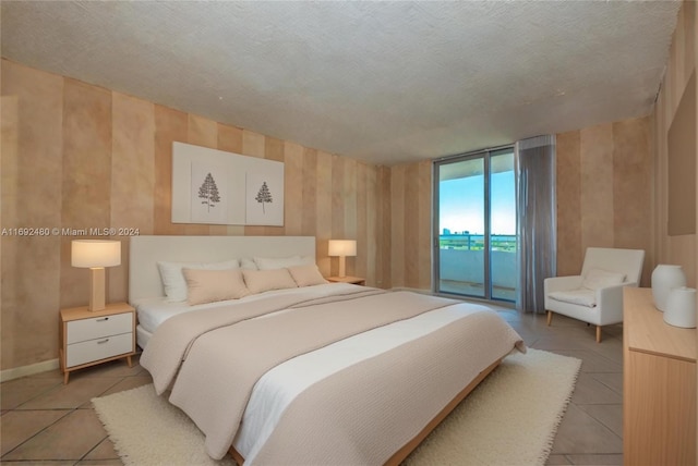 bedroom featuring access to exterior, tile patterned flooring, and a textured ceiling