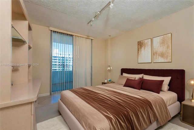 bedroom with light carpet, a textured ceiling, and track lighting