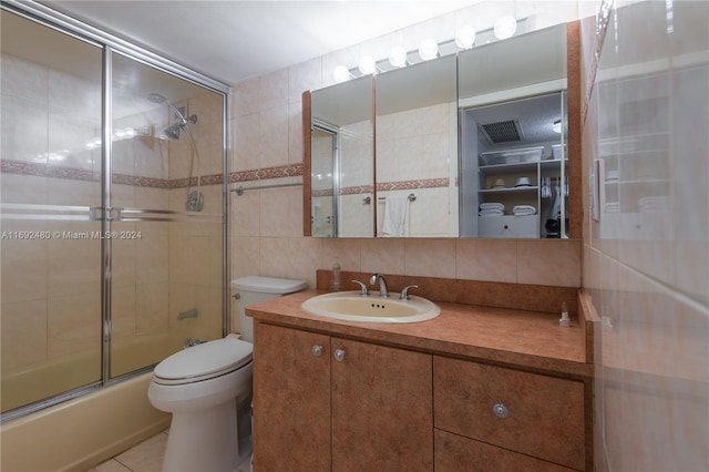 full bathroom featuring backsplash, bath / shower combo with glass door, toilet, vanity, and tile walls