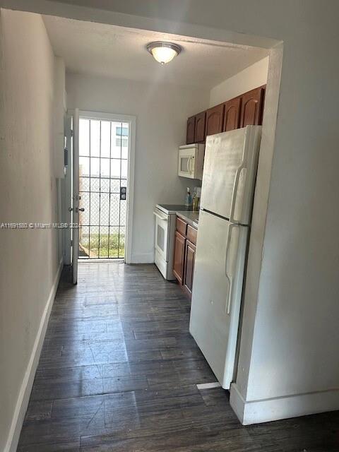 kitchen with white appliances and dark hardwood / wood-style floors