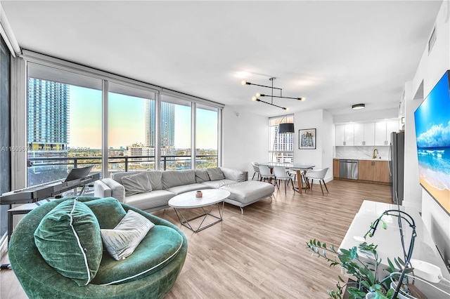 living room featuring a wall of windows, light hardwood / wood-style floors, and an inviting chandelier