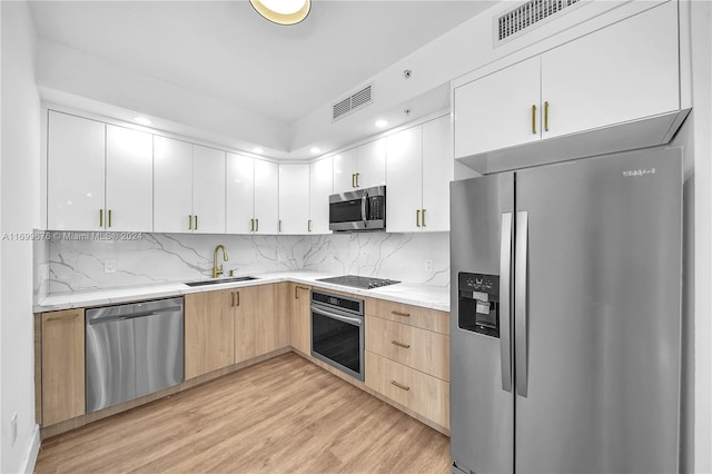 kitchen with stainless steel appliances, sink, light brown cabinets, light hardwood / wood-style flooring, and white cabinets