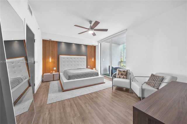 bedroom with ceiling fan, expansive windows, and light wood-type flooring