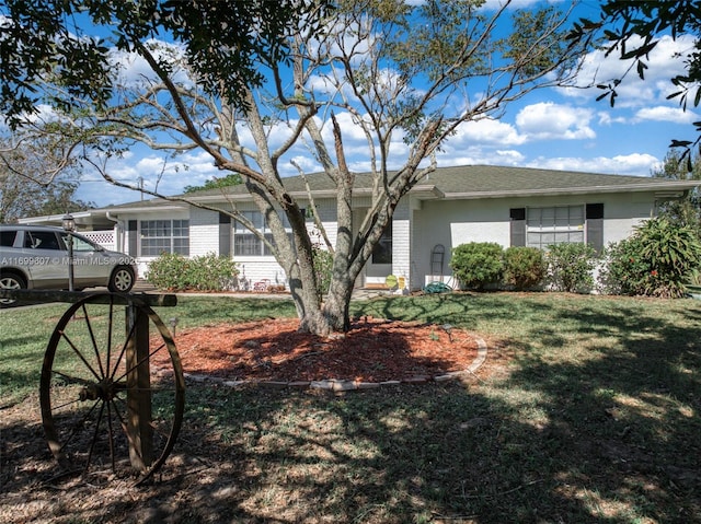 view of front of home featuring brick siding, stucco siding, a front yard, and roof with shingles